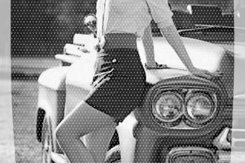 Statuesque redhead reclines on classic automobile